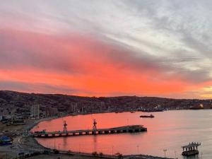 una puesta de sol sobre un cuerpo de agua con un muelle en HOM l Estudio con Vista al mar 3PAX, en Valparaíso