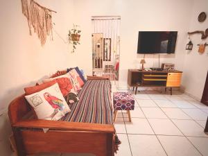a living room with a couch and a tv at Chalé Pequi, Romântico e espaçoso, com ar cond conforto e aconchego in Cavalcante