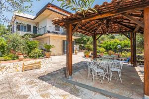 a patio with a table and chairs under a wooden pergola at Villa Etna Maison in Montargano