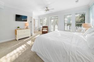 - une chambre blanche avec un lit, une commode et des fenêtres dans l'établissement Texas Tides, à Destin