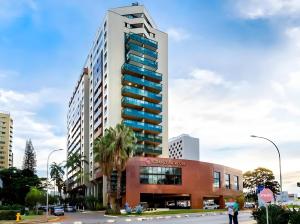 a tall building with blue windows on a city street at BSB STAY Flats Particulares - Grand Mercure SHN in Brasilia