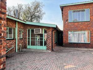 een bakstenen gebouw met een groene deur erop bij KwaDines Guesthouse in Standerton