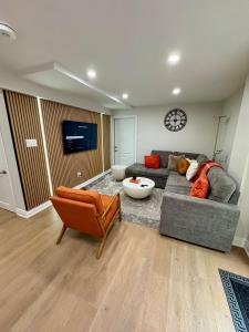 een woonkamer met een grijze bank en een klok bij 2 BR Private Basement Suite | Minutes from YYZ in Brampton