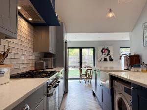 a kitchen with blue cabinets and a stove top oven at Historic Hampshire Cottage with Private Putting Green in Eversley