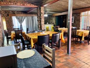 een eetkamer met tafels en stoelen en bakstenen muren bij KwaDines Guesthouse in Standerton