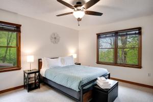 a bedroom with a bed with a ceiling fan and windows at Elk Ridge Retreat -Hot Tub- Firepit-Fireplace in Maggie Valley
