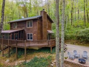 a log cabin with a deck in the woods at Elk Ridge Retreat -Hot Tub- Firepit-Fireplace in Maggie Valley