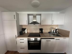 a kitchen with white cabinets and a sink at FeWo Friedchen in Mücke