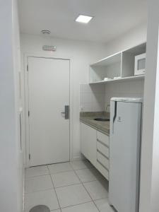 a white kitchen with a refrigerator and a microwave at Fusion e Vision Flats in Brasilia