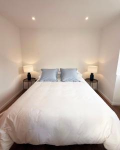 a bedroom with a large white bed with two lamps at Cottage - A Casa da Avó in São Vicente