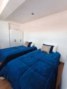 two beds in a white room with blue blankets at La Casita De Colores Cusco in Cusco