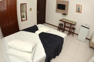 a bedroom with a white bed with black sheets at Hotel Dom Fish in Florianópolis