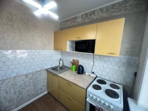 een kleine keuken met een spoelbak en een fornuis bij LuxHome на УК in Öskemen