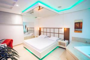 a bedroom with a white bed and a bath tub at Drops Motel Ribeirão PTO in Ribeirão Preto +18 photos