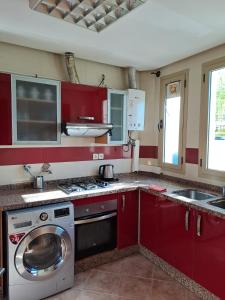 - une cuisine avec des placards rouges et un lave-linge dans l'établissement Séjour Prestige Vue Mer, Jacuzzi, Piscine, à Oulad Akkou