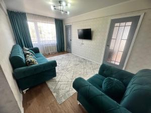 een woonkamer met een bank en een tv bij LuxHome на УК in Öskemen