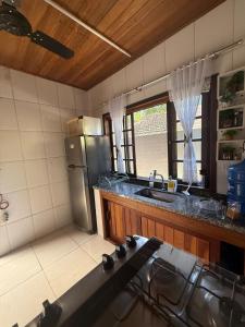 a kitchen with a sink and a refrigerator at Casa Marrom dos Mellos, Campos do Jordão in Campos do Jordão