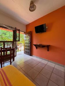 Casa Triz في بويرتو إسكونديدو: غرفة نوم بجدران برتقالية وتلفزيون على الحائط