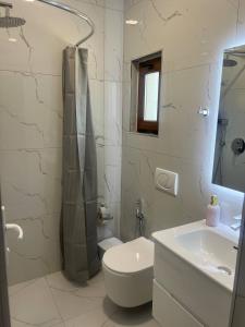 a white bathroom with a toilet and a sink at Cozy Room for Three in Kamëz