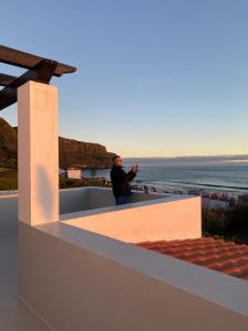 a man taking a picture of the ocean from a roof at A casa da Xã in Almagreira