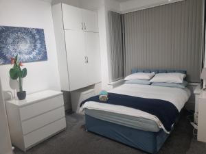 a bedroom with a blue bed and white cabinets at Generous double bedroom with ensuite - home from home! in Birmingham