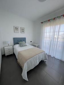 a white bedroom with a bed and a window at Apartamento Celma in Adeje