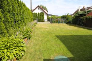 Un patio con césped verde, una valla y arbustos. en Pokoje u SŁONIA, en Stegna