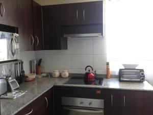 een keuken met bruine kasten en een fornuis met oven bij Departamento en Condominio Mar Serena in La Serena
