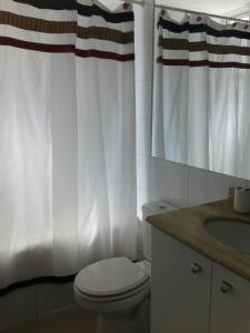 baño con aseo y cortina de ducha blanca en Departamento en Condominio Mar Serena, en La Serena