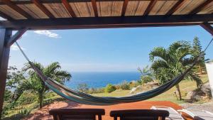 a hammock on a porch overlooking the ocean at Habitation Noëlesse - vue mer à Marie-Galante - authentique et romantique in Beauregard