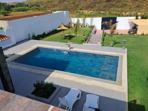 a swimming pool in a yard with two chairs at Villa Ghailan in Asilah
