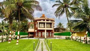 a large house with palm trees in front of it at Casa Nada Beach Villa in Udupi +19 photos