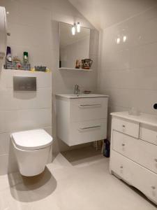 a white bathroom with a toilet and a sink at Béatrice et Michel in Émerainville