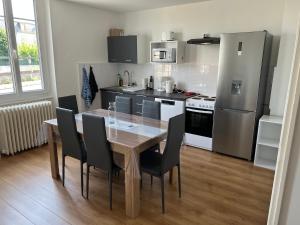 a kitchen with a wooden table and black chairs at PERLE RARE centre-ville in Paray-le-Monial +1 photo