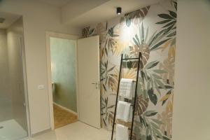 a bathroom with a tropical wallpaper on the wall at Giardini Rooms in Cremona