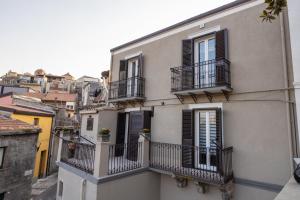 a white building with black shutters and balconies at Alcantara Domus in Roccella Valdemone