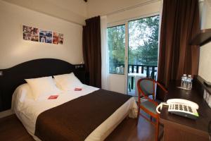 Schlafzimmer mit einem Bett, einem Telefon und einem Fenster in der Unterkunft Village Club Le Saint Ignace in Ascain