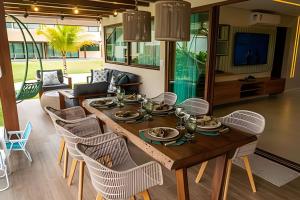 ein Esszimmer mit einem Holztisch und Stühlen in der Unterkunft Bangalô Essenza do Sol |Luxo & Charme em Carneiros in Tamandaré