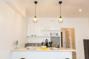 Una cocina con gabinetes blancos y tres luces colgantes. en L'escale - Centre ville - 3 étoiles, en Bourg-en-Bresse 12 fotos más