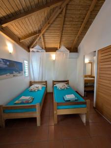 zwei Betten in einem Zimmer mit Holzdecken in der Unterkunft Villa dans un have de paix avec piscine in Saint-François