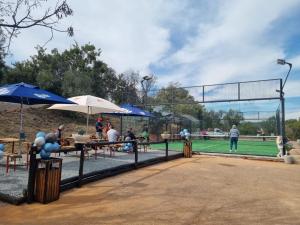 a group of people sitting at tables on a tennis court at Elements golf reserve in Bela-Bela