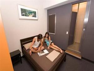 two women sitting on a bed in a hotel room at Global Backpackers Port Douglas in Port Douglas