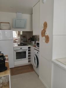 a white kitchen with a stove and a washing machine at T2 loggia et piscine in La Rochelle