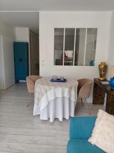 a living room with a table and chairs and a mirror at T2 loggia et piscine in La Rochelle