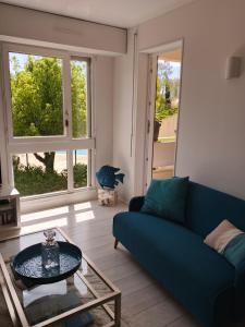 a living room with a blue couch and a glass table at T2 loggia et piscine in La Rochelle