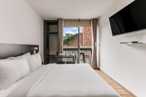 a bedroom with a large white bed and a window at Primavera By Homirent in Querétaro