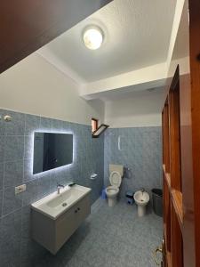 a bathroom with a sink and a toilet and a tv at Dori 102 Apartment in Polisi i Vogël