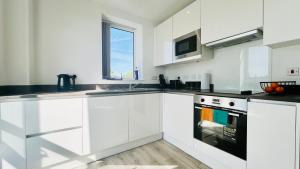 a white kitchen with white cabinets and a window at Entire Luxury 2 Bedroom Apartment - Quiet & Central with Free Parking in Birmingham