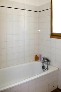 a white bath tub in a white tiled bathroom at La Bignone in Régusse
