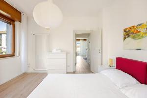 a white bedroom with a white bed and a red headboard at Dolomiti Experience bike, hike, fly & relax in Feltre